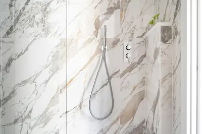 a shower in a bathroom with white marble walls at iFlat Wood and Marble Riverfront in Rome