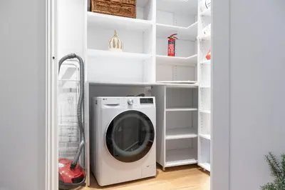 a washing machine in a laundry room with white shelves at iFlat Wood and Marble Riverfront in Rome