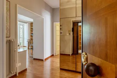 a living room with a wooden door and a kitchen at GuestHost - Rione Prati Comfy Apartment in Rome