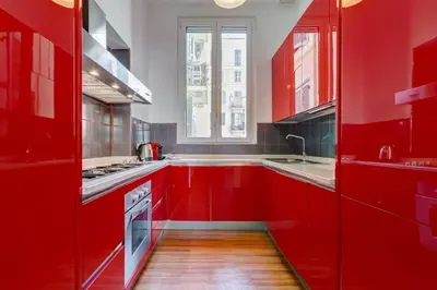 a red kitchen with red cabinets and a window at King's House - San Giovanni/Re di Roma in Rome