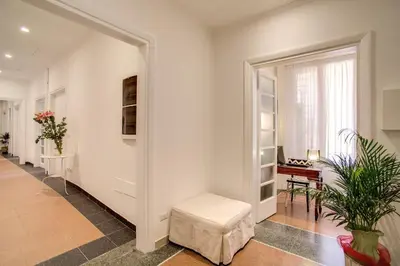 a hallway with white walls and a door with a stool at Roma In Una Stanza Guesthouse in Rome