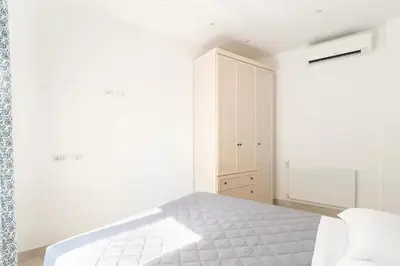 a white bedroom with a bed and a cabinet at First Floor Apartment in Rome