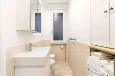 a white bathroom with a sink and a toilet at First Floor Apartment in Rome