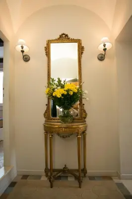 a mirror on a table with a vase of flowers at Your Prestigious Penthouse at the Spanish Steps in Rome