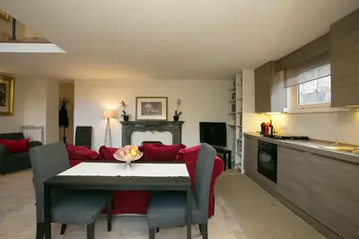 a kitchen and living room with a table and a red couch at Your Prestigious Penthouse at the Spanish Steps in Rome