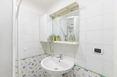 a white bathroom with a sink and a mirror at Colosseum Perfect Apartment in Rome