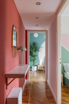 a hallway with a pink wall with a table and a mirror at ARIA Penthouse & Garden in Rome
