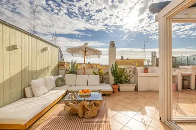 a patio with a couch and a table on a roof at ARIA Penthouse & Garden in Rome