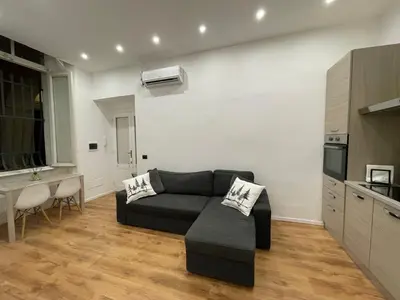 a living room with a black couch and a kitchen at GM house Rome in Rome