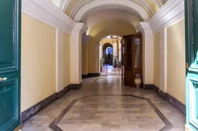 an empty hallway with an arched ceiling and a hallway with green doors at GM house Rome in Rome