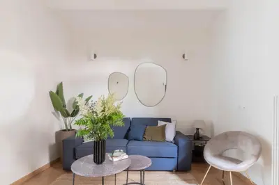 a living room with a blue couch and two mirrors at iFlat Blue Cozy Loft near Saint Peter in Rome