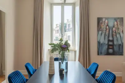 a dining room table with blue chairs and a window at Spanish Steps Caesar Suites in Rome