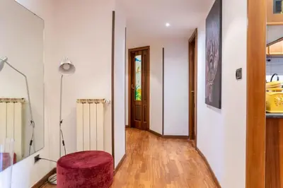 a living room with a red stool and a hallway at Trastevere - Viaggio a Roma Antica in Rome