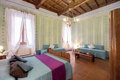 a bedroom with a bed and a couch and windows at Casa Savelli in Rome