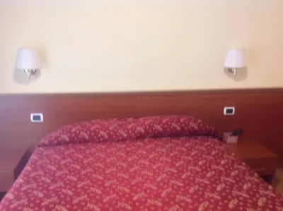 a bedroom with a red bed with two lamps on the wall at Guglielmo Marconi House in Rome