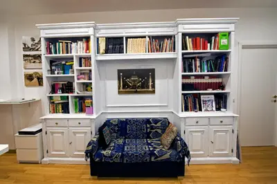 a book shelf with a chair in a room with books at The Photos Room B&B in Rome