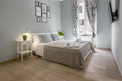a white bedroom with a bed and a window at AD MAIORA SUITE in Rome