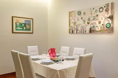 a dining room table with white chairs and a painting at Viale Tirreno - Appartamento con Patio in Rome