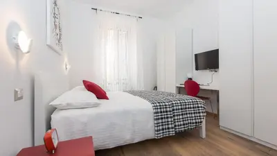 a white bedroom with a bed and a red chair at Saint Peter Prestigious by Rental in Rome in Rome