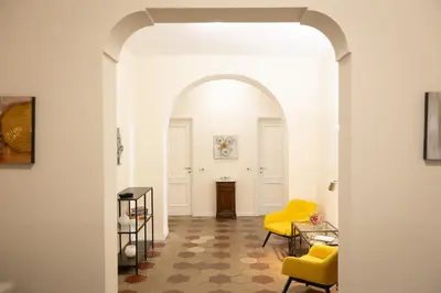 an archway leads into a living room with yellow chairs at Principe Amedeo By Rental in Rome in Rome