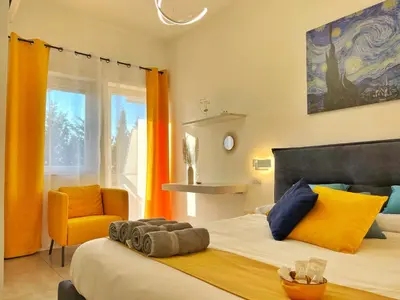 a bedroom with a large bed and a yellow chair at L' oasi di Roma - Modern apartment with pool&parking in Rome