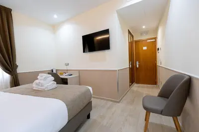 a hotel room with a bed and a chair and a television at Hotel Maximus in Rome