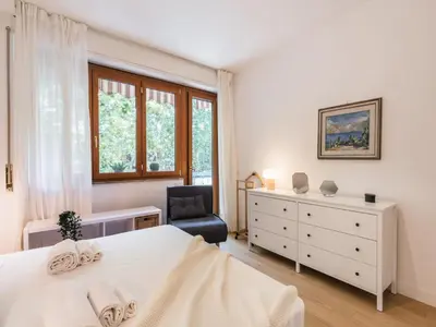 a white bedroom with a bed and a chair at The Best Rent - Apartment in Trastevere area in Rome