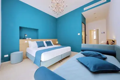 a blue bedroom with two beds and a chandelier at Youroom Quattro Fontane Appartamento in Rome