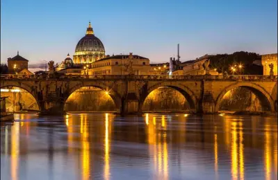 a bridge over a river with a building and a dome at La Suite di San Pietro in Rome
