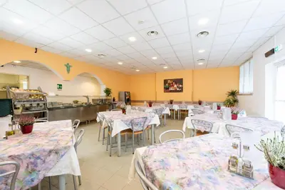 a restaurant with tables and chairs and a kitchen at Casa per Ferie Opera Don Calabria in Rome