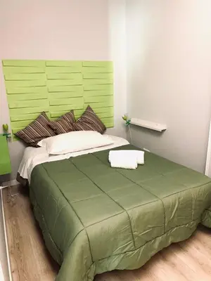 a bed with a green headboard in a room at NASONI DI ROMA (VICINISSIMO BASILICA SAN GIOVANNI IN LATERANO) in Rome