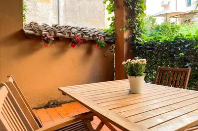 a wooden table with a vase of flowers on a patio at [Luxury House & Secret Garden] - Strategic location, 100m to Metro B in Rome