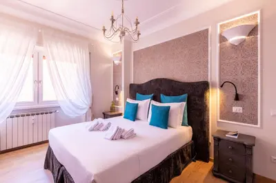 a bedroom with a large white bed with blue pillows at Trastevere Paper Suites in Rome