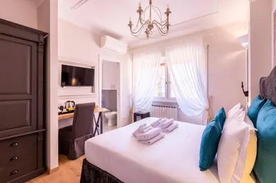 a bedroom with a white bed with a chandelier at Trastevere Paper Suites in Rome