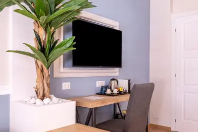 a dining room with a table and a tv on a wall at Trastevere Paper Suites in Rome
