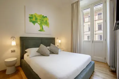 a bedroom with a white bed with a tree on the wall at Porta Castello Charme in Rome