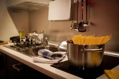 a pot of pasta on a kitchen counter next to a sink at Chroma Italy - Chroma Apt Campo de' Fiori in Rome