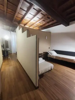 a large room with two beds and a wooden floor at Chroma Italy - Chroma Apt Campo de' Fiori in Rome