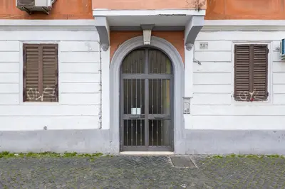 a white building with a door and two windows at The Best Rent - Three-bedroom apartment in Porta Maggiore area in Rome