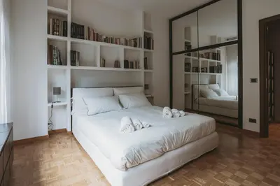 a bedroom with a large white bed with bookshelves at EasyTopStay - Peaceful Retreat near San Pietro in Rome