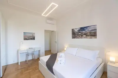 a white bedroom with a bed and a desk at Colosseo Modern by Rental in Rome in Rome