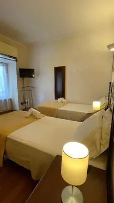 a hotel room with three beds and a lamp at Holiday Suite Roma in Rome