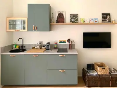 a kitchen with blue cabinets and a flat screen tv at La Dolce Vita - Old Testaccio Luxury Apartment in Rome