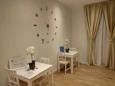a room with two tables and a clock on the wall at BePlace Holy See in Rome