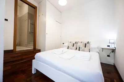 a white bedroom with a white bed and a shower at FRAM Apartment Fori Imperiali in Rome
