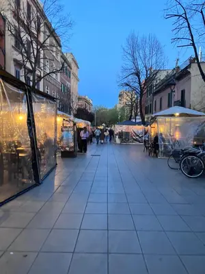 a street with stalls in a city with people walking at M&M Pigneto Roma in Rome
