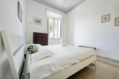 a white bedroom with a bed and a window at Cozy Merulana in Rome