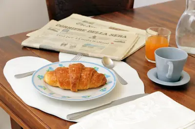 a table with a plate of food and a cup of orange juice at Cozy Merulana in Rome