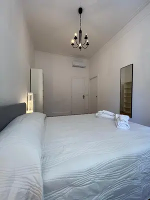 a large white bed in a white bedroom with a chandelier at Flaminia@213 in Rome