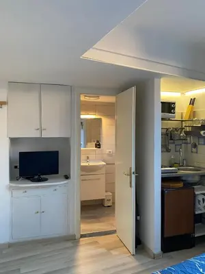 a kitchen with white cabinets and a tv in a room at Trastevere onlyone in Rome